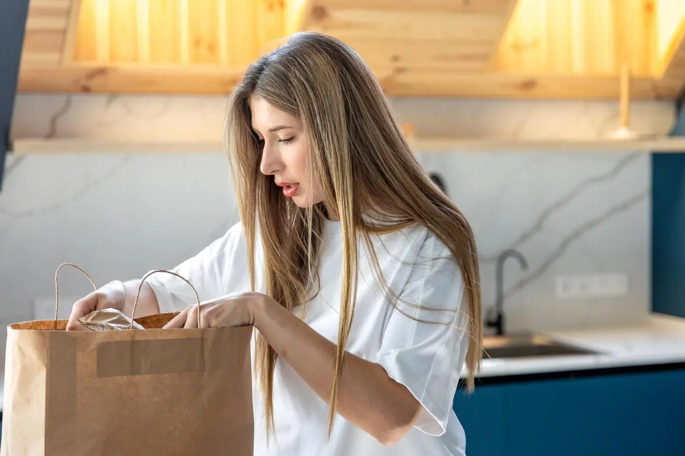 A surprised woman unpacking a grocery bag at home, following a plastic-free lifestyle.